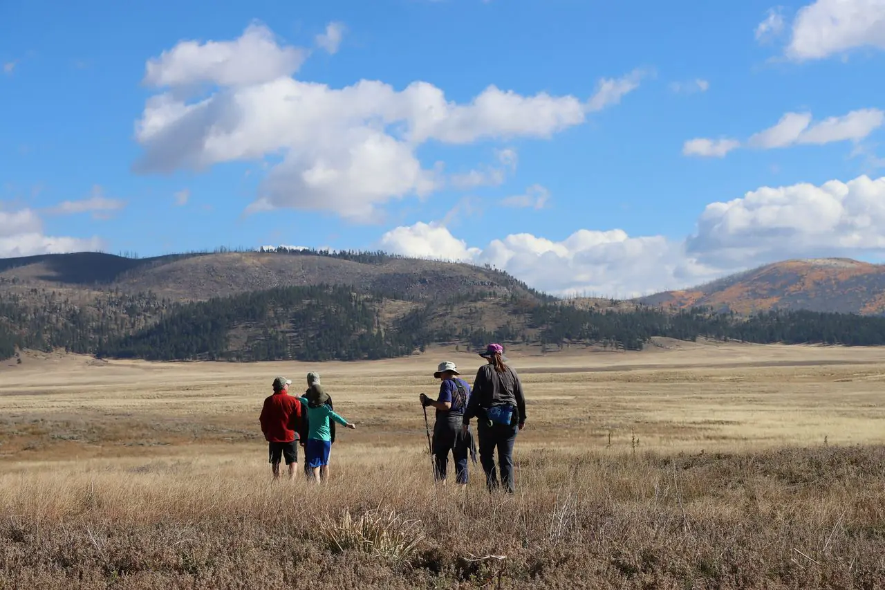 A family hiking together across a broad grassland trail in New Mexico
